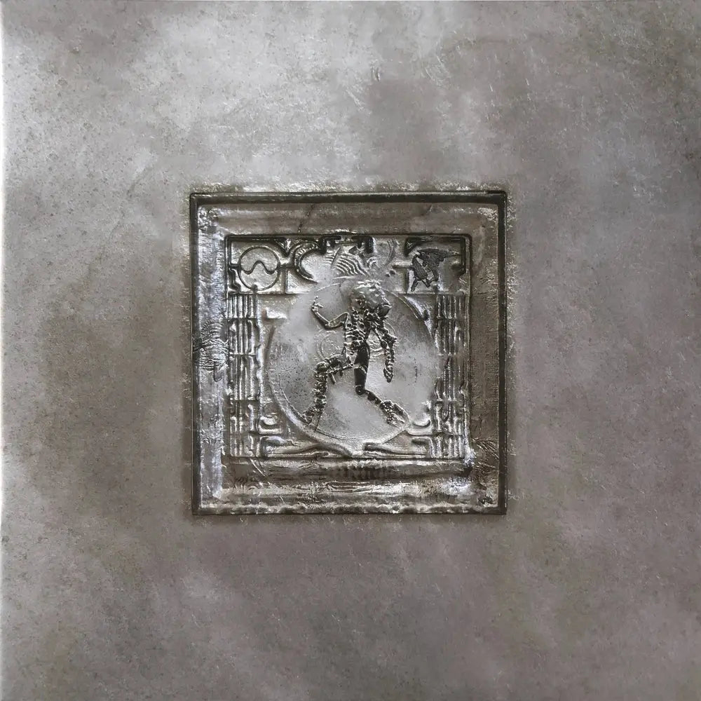 Un disco de vinilo plateado con un relieve central de una figura danzante.