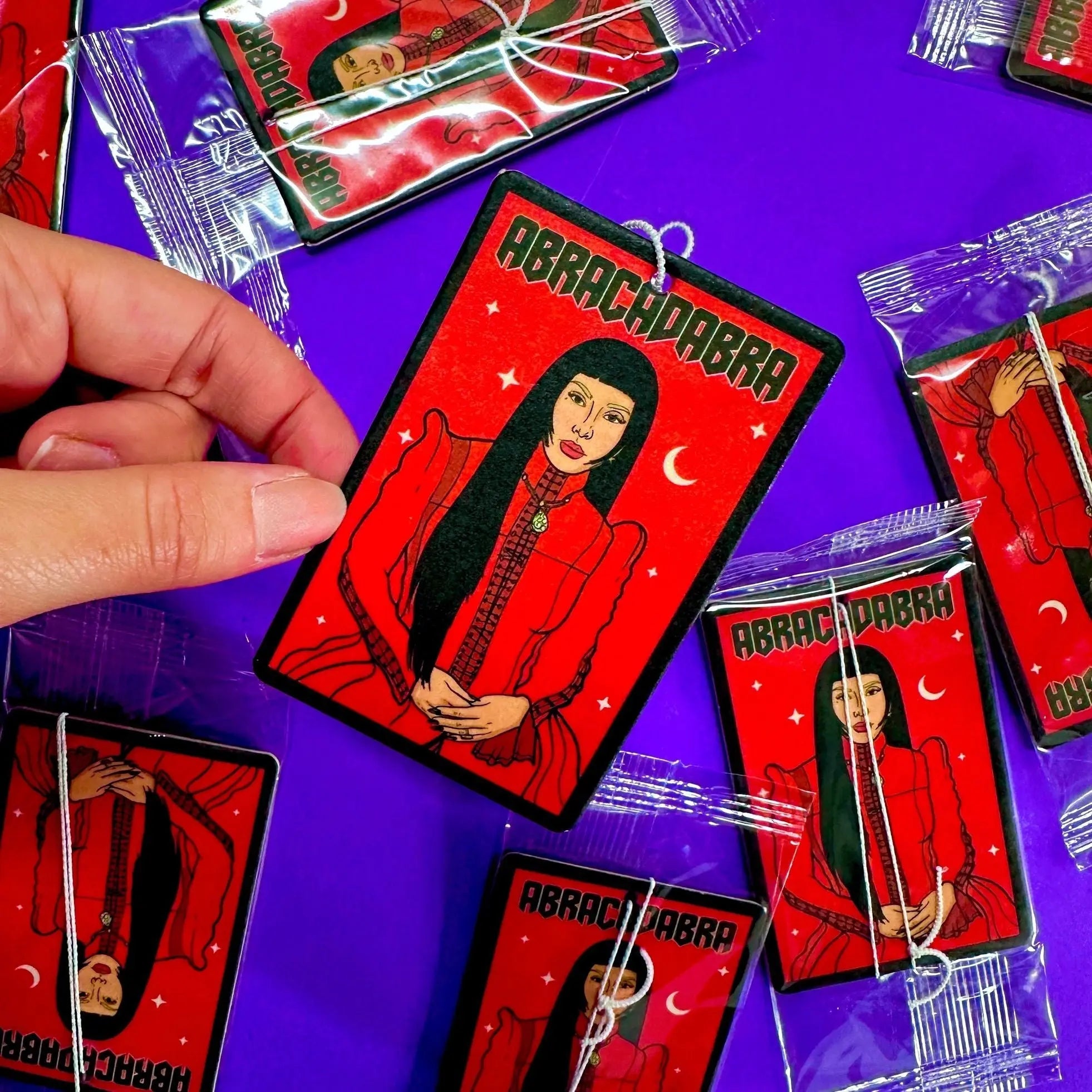 Ambientador rectangular rojo con ilustración de Lady Gaga y la palabra "Abracadabra".