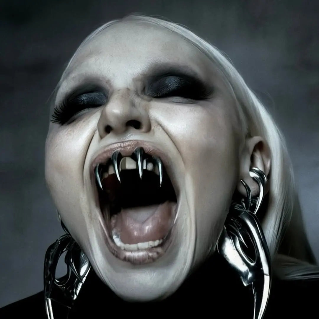 Una mujer con maquillaje oscuro y colmillos metálicos grita, llevando pendientes grandes y plateados.