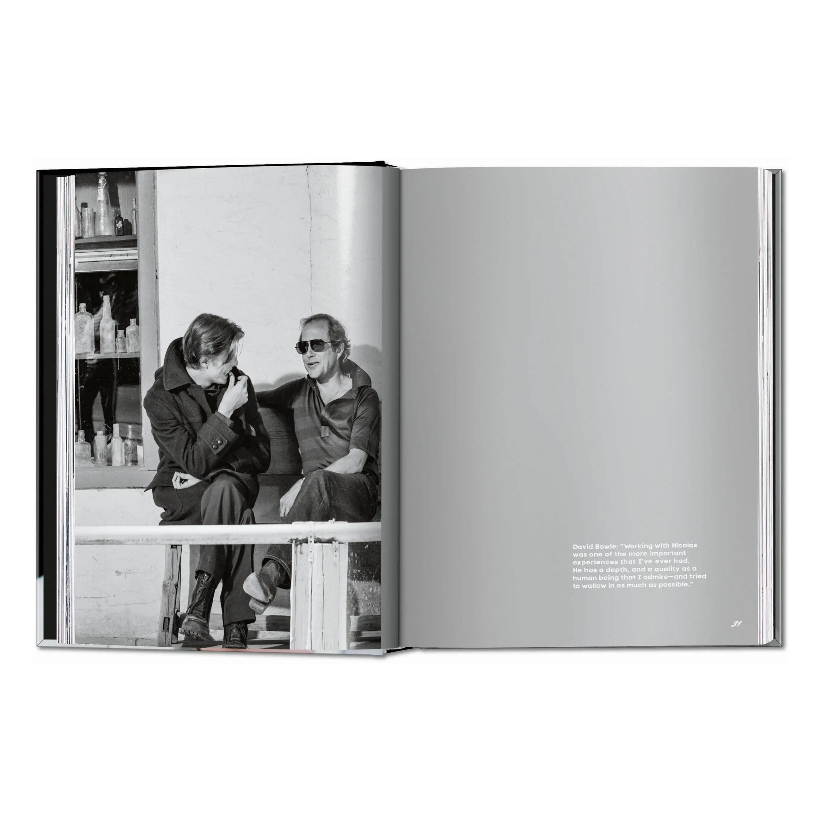 An open book shows a black and white photo of two men and a quote on a gray page.