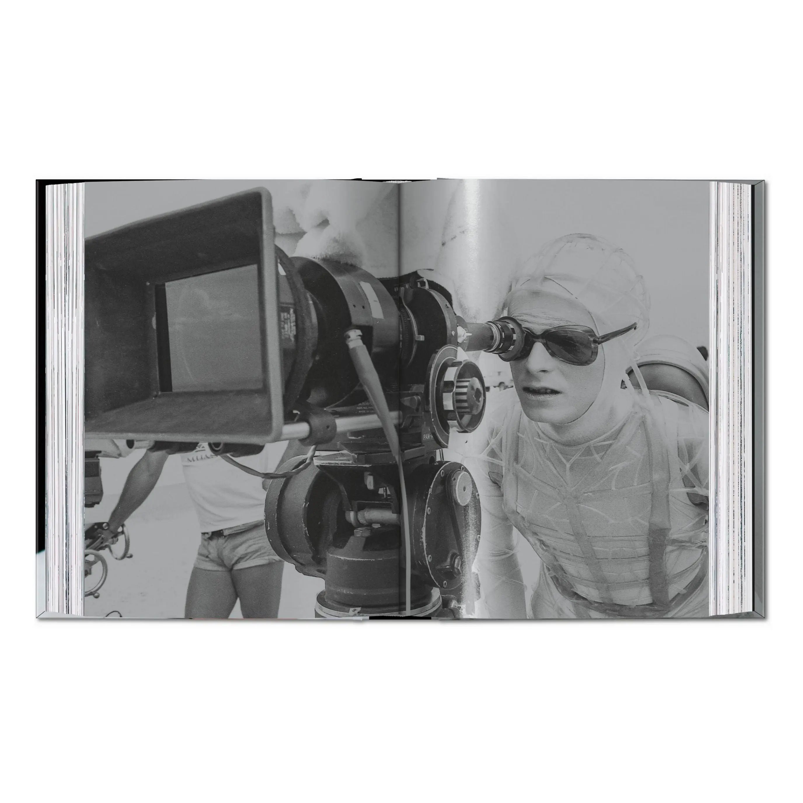 An open book shows a black and white photo of David Bowie looking into a film camera.