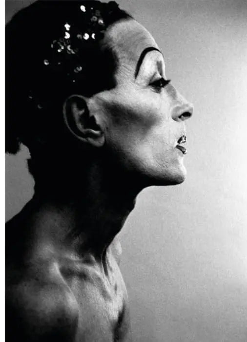 Retrato en blanco y negro de un travesti con maquillaje dramático y lentejuelas.
