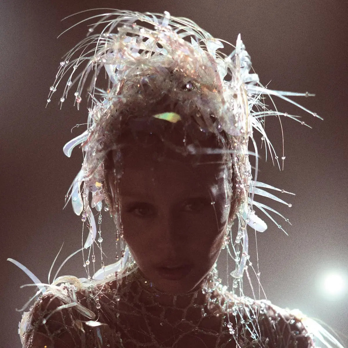 Miley Cyrus con un tocado y vestido brillantes y transparentes.