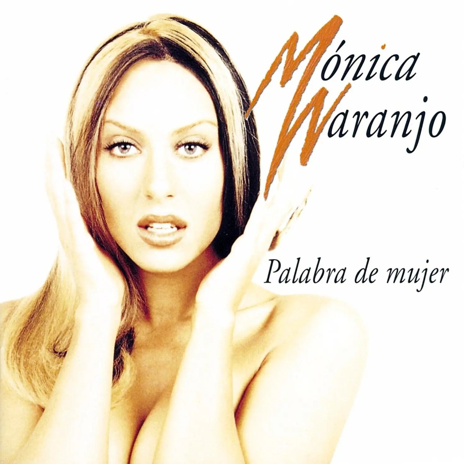 Mónica Naranjo con cabello rubio y negro, manos en la cara, sobre fondo blanco.