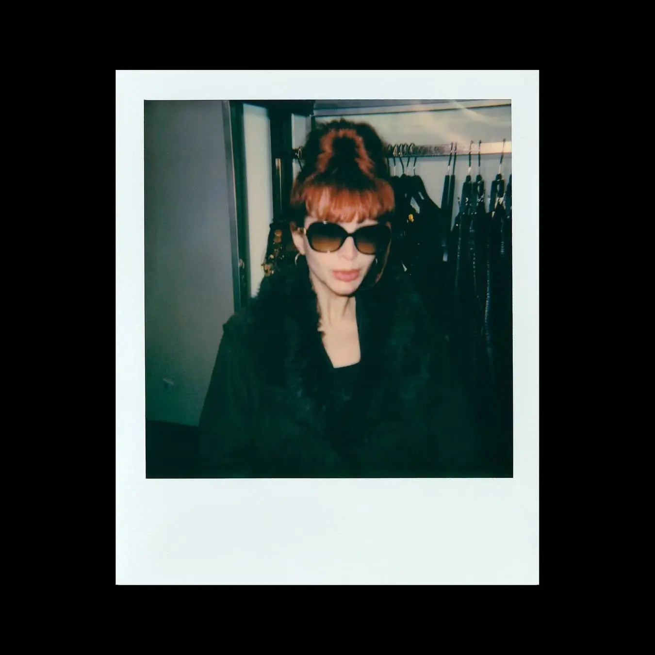 Una mujer con gafas de sol y cabello rojizo en un polaroid.