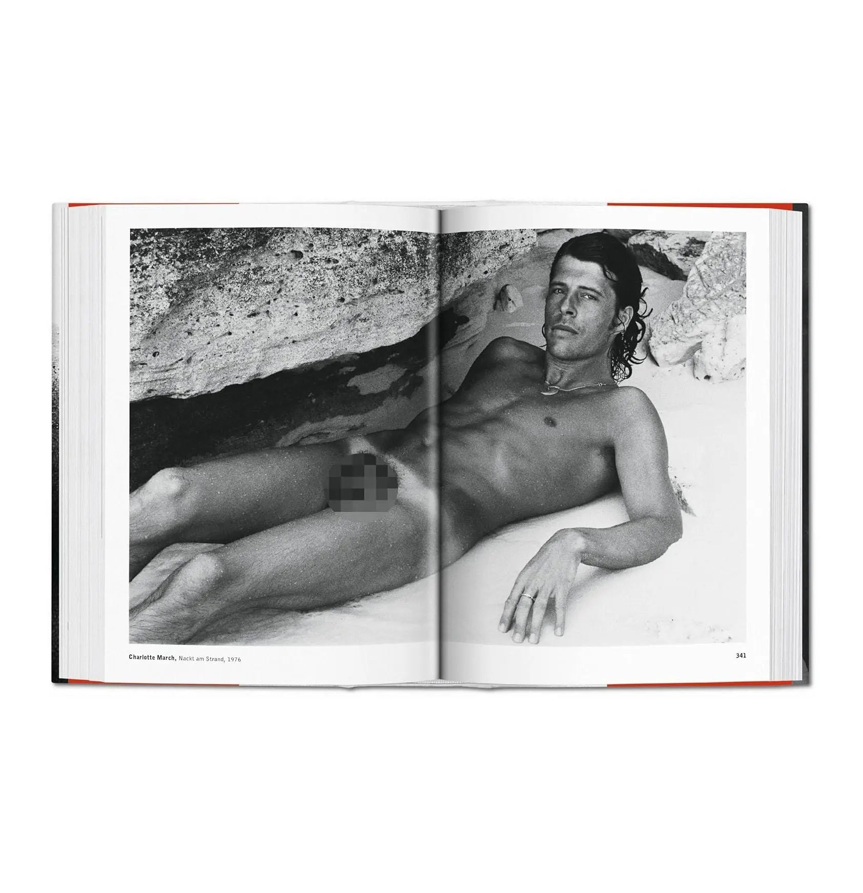 A black and white photo of a man lying on a beach, displayed in an open book.