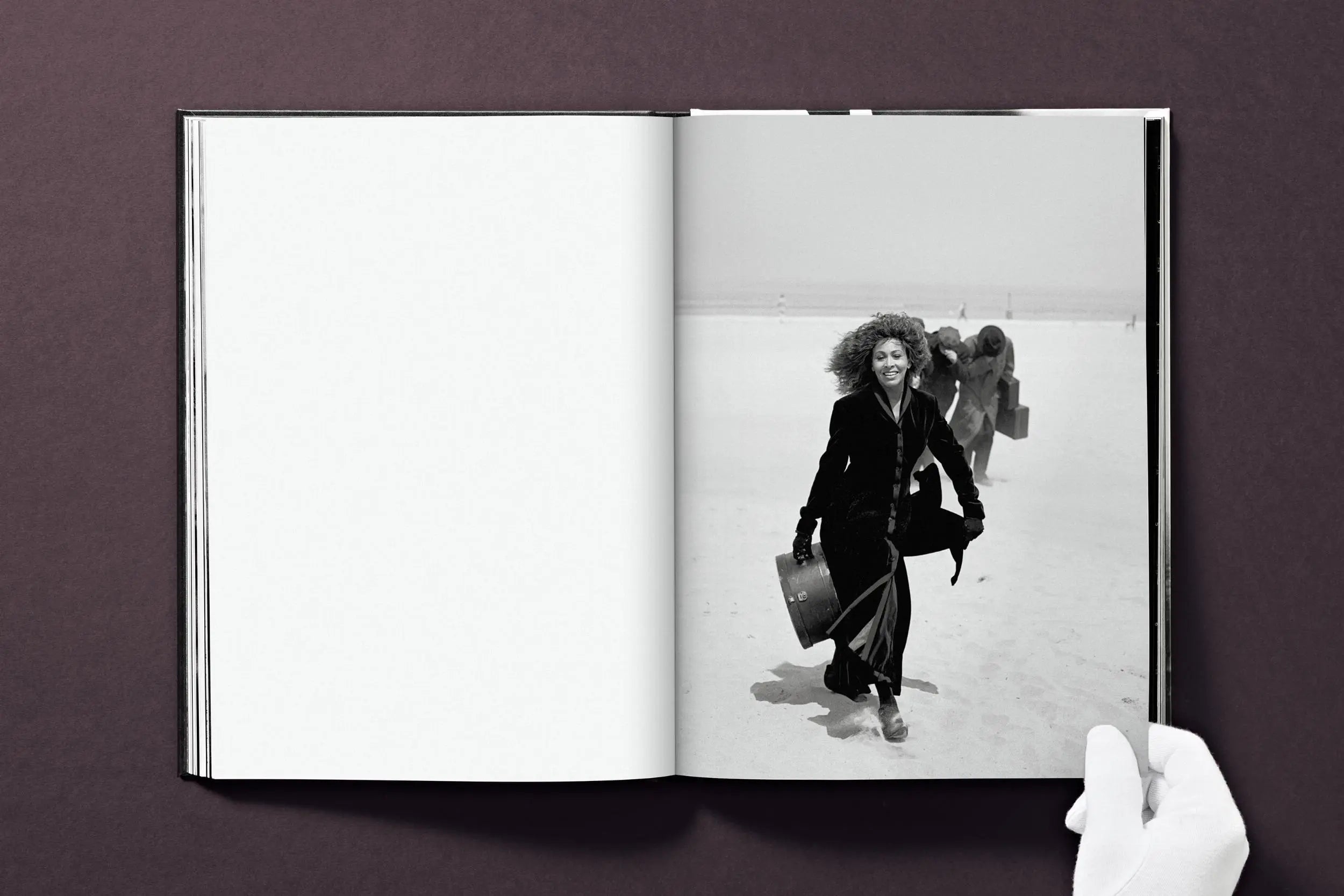 A person in white gloves holds open a book displaying a black and white photo of Tina Turner.